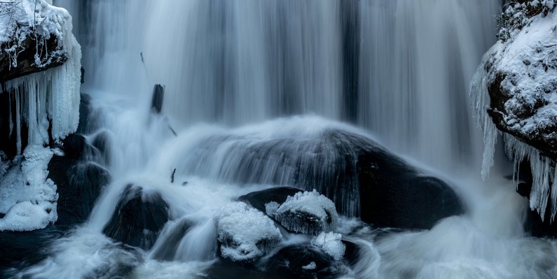 A cascade falls onto icy, snowy rocks in Whatcom Falls Park