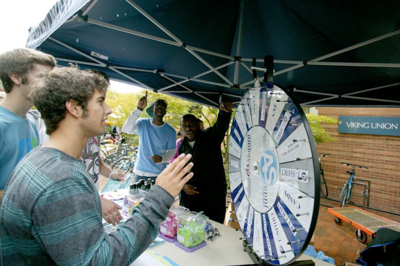 Western Washington University student Tait Trautman spins the Associated Students prize wheel at the Red Square Info Fair on Sept. 20, 2010. Cheering Trautman on are AS employees Jonathan J. Oliver, left, and Bernard Igegwuoha. The info fair took place in