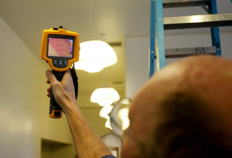 <p>
	Richard Porter, a maintenance mechanic with Western Washington University Facilities Management, uses a scanner to determine what areas of the ceiling are wet. Purple on the screen indicates areas of dampness. Photo by Matthew Anderson | WWU</p>
