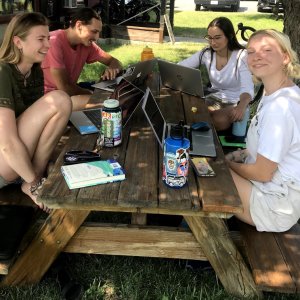 Four students sit at a picnic table on a summer summer day in the Methow Valley