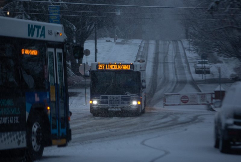 A bus makes its way down High Street towards the bus stop in the snow