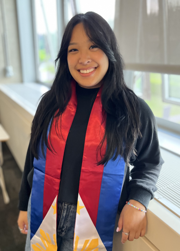 Alliyah Olegario smiles for the camera, wearing a red, white and blue commencement sash