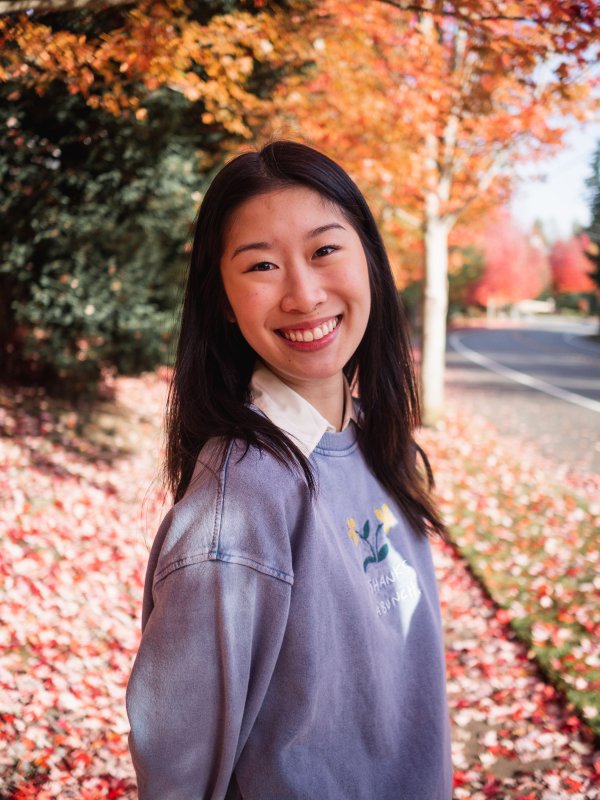 Annette Lam smiles for the camera with fall foliage in the background