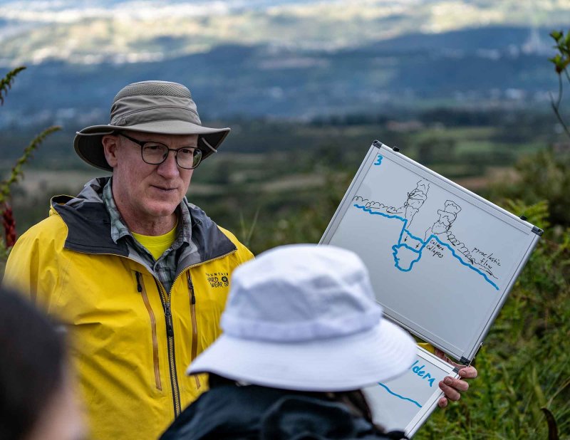 Scott holds up a white board with an illustration of how a volcano's caldera can collapse 
