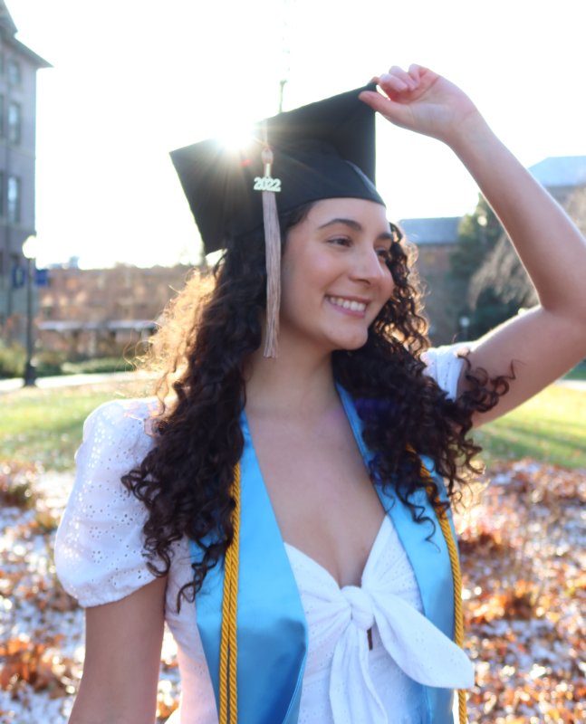 Mariana Urrea smiles and looks to the right, wearing a graduation cap, sash and honor cords