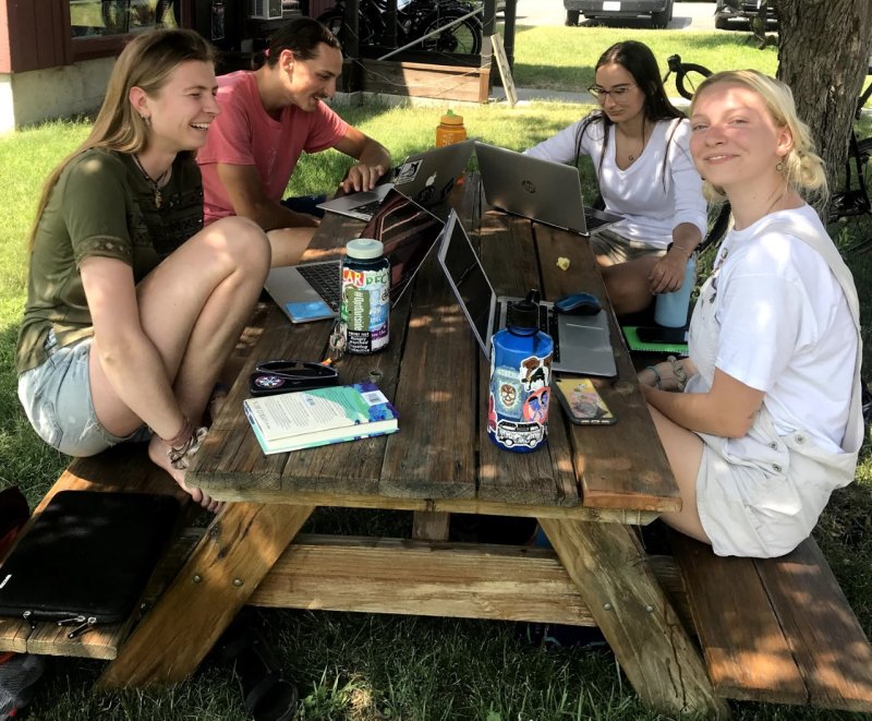 Four students sit at a picnic table on a summer summer day in the Methow Valley
