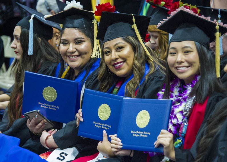three students show off their diplomas at commencement