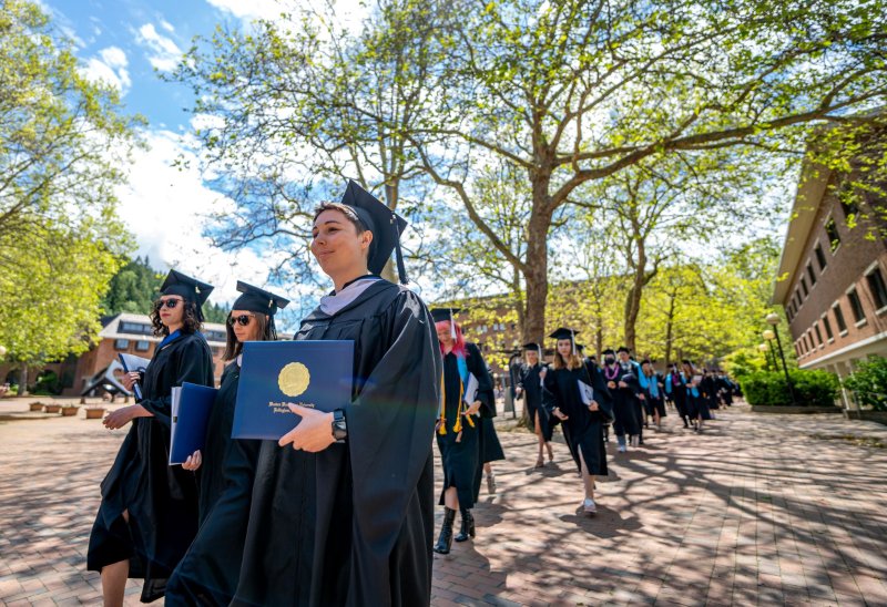 Graduating students walk along Haggard Hall as they recess after commencement.