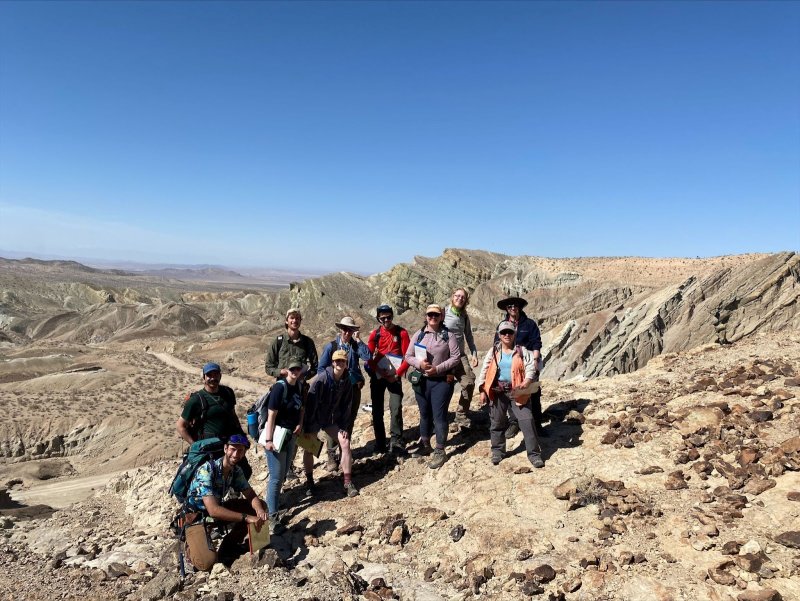 Elizabeth Schermer stands with a cohort of her students on a geology field study in the Mojave Desert on a clear day.