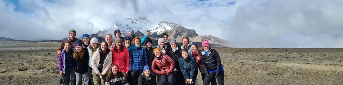 The group gathers on flat ground with snow-capped Chimborazo in the background as the clouds clear up.