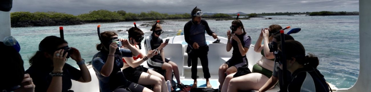 Students listen to an instructor as they sit on a boat before going snorkeling in the Galápagos.