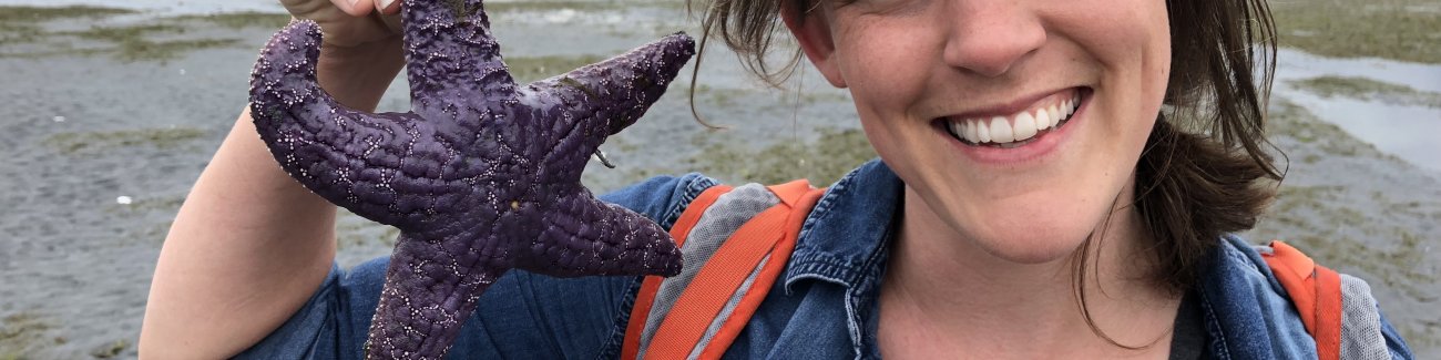Chelsea Hutchinson holds a purple starfish on a beach