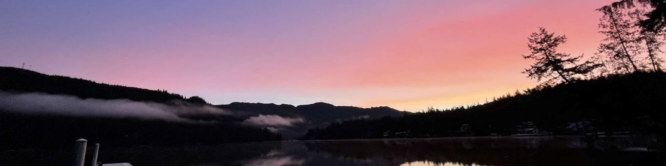 The sun rises in shades of pink and purple over a placid Lake Samish.