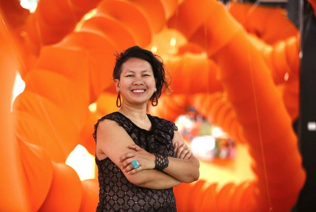 Anida Yoeu Ali stands with arms crossed in front of a huge set of orange tubes