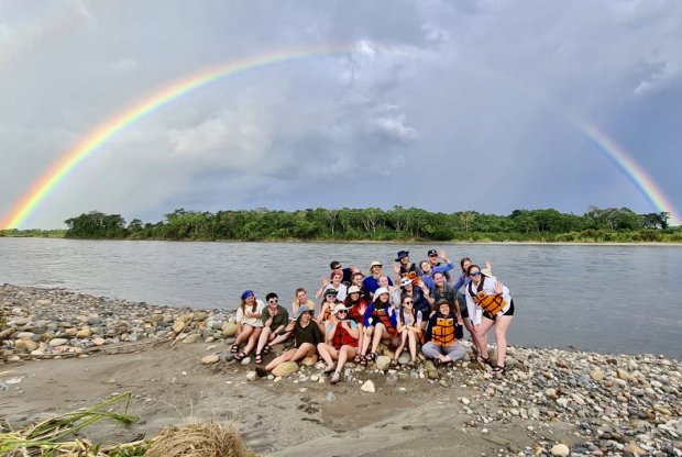 Students pose for a picture on the shores of Rio Napo, one of Ecuador‘s largest tributaries of the Amazon, beneath a rainbow that arches over the jungle on the other shore.
