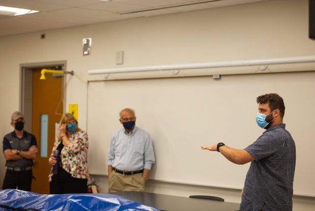 President Sabah Randhawa listens to anatomy/physiology staff standing around a classroom 