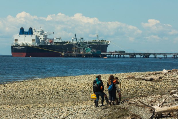 a tanker offloads oil at Cherry Point as students walk on the beach