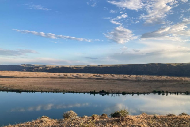 The Megaripples formation in Eastern Washington, with water in the foreground and blue skies above.