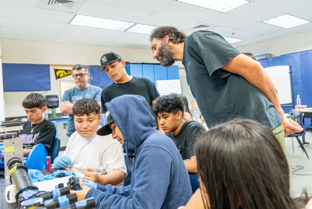 Western Assistant Professor of Biology Nick Galati stands behind a group of Mount Vernon High School students as they work on building a microscope.