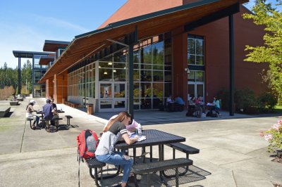 students sit and study at tables outside the WWU building at Olympic College Poulsbo