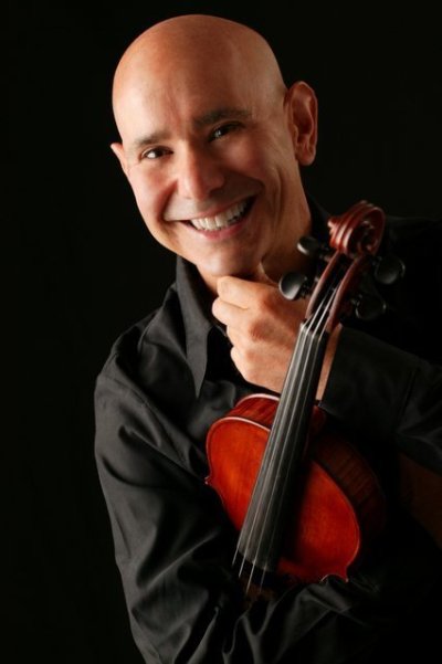 Hal Grossman hold his violin and smiles at the camera