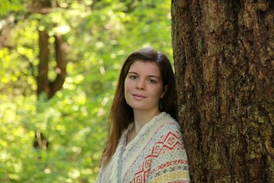 Alea Kirby leans against a tree and smiles for the camera