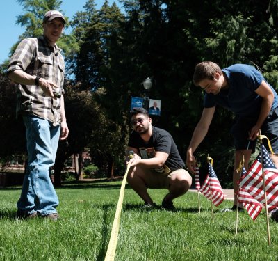Students carefully measure a grid pattern in Old Main lawn as they place the flags. 