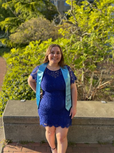 Nancy Stoita wears a light blue commencement sash and blue dress on campus