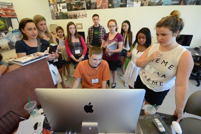 Western journalism student Hannah Johnson, the lead designer for Klipsun Magazine during summer quarter, describes production to a group of WJEA attendees in the Klipsun office in the Communications Facility on campus during summer quarter 2014. File phot