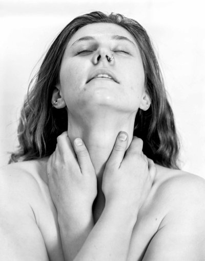 Black and white portrait of Cierra Coppock - looking upwards with their eyes closed and holding their hands gently around their neck