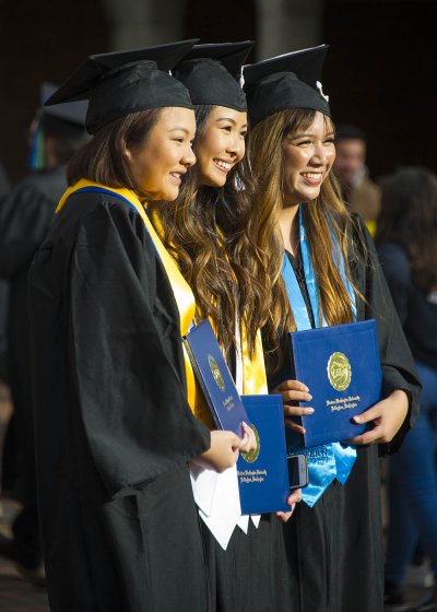 three friends pose with their diplomas