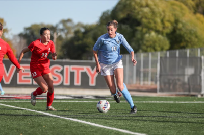 A Western women's soccer player pushes the ball up the field