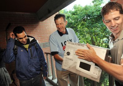 On move-in day 2009, Anton Abuamsha, 18, of Anchorage, Alaska, gets some help moving a microwave into his room at Ridgeway Beta from Western Washington University president Bruce Shepard, center. Oly Steinmetz, right, of Bellingham, fishes with the brothe